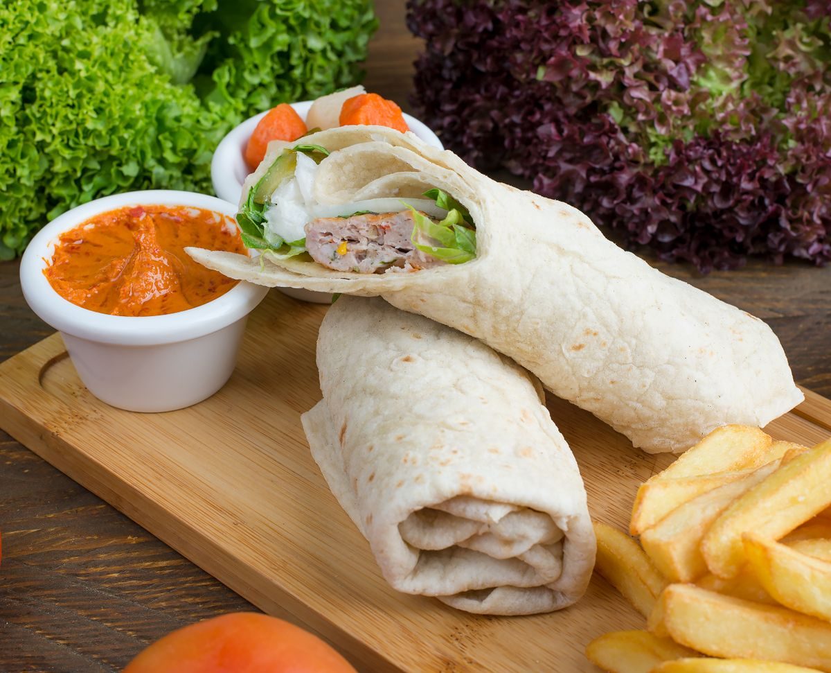 Frisk sandwich og wrap på træbræt med salatblade