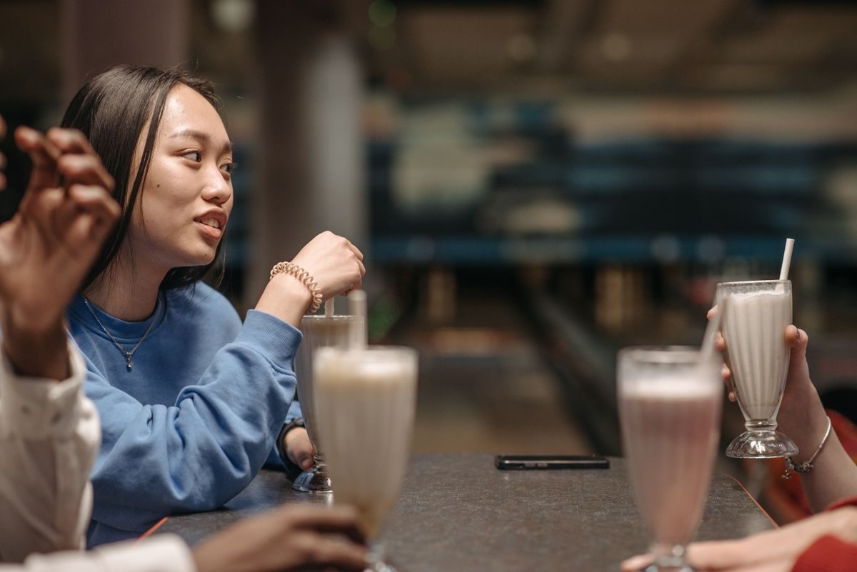 Milkshake i højt glas med sugerør og flødeskum på cafébord