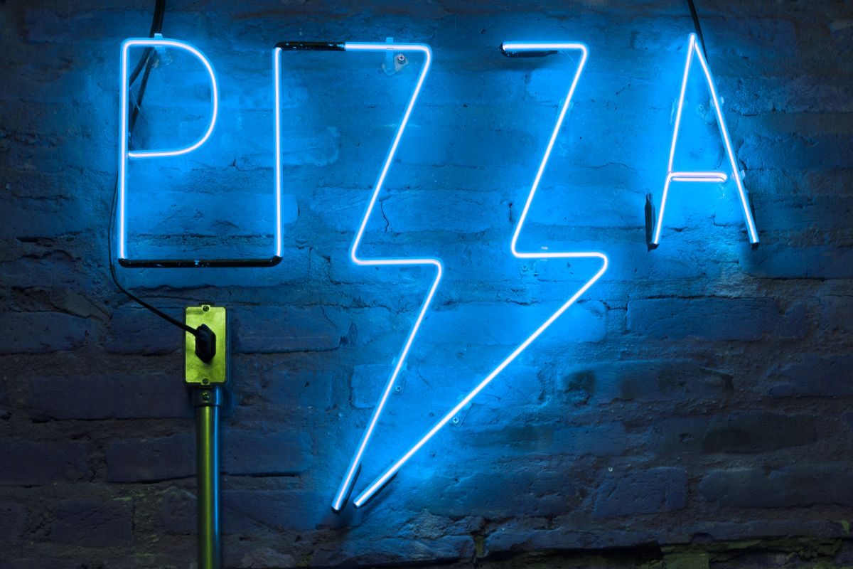 Moderne pizzarestaurant med neonskilt og travl stemning
