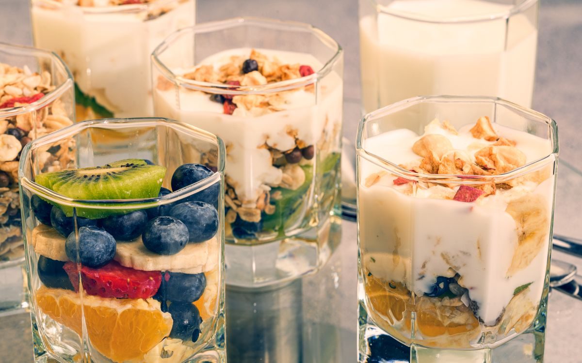Morgenmad med yoghurt, frisk frugt, juice og croissant på lyst bord
